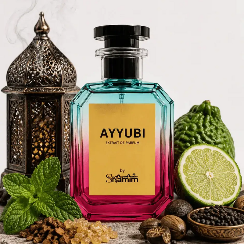 A faceted glass perfume bottle with a black cap, featuring a yellow label that reads 'AYYUBI EXTRAIT DE PARFUM' and 'by Shammim'. The bottle has a blue-to-pink gradient.