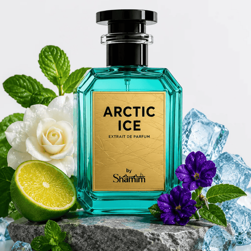 A bottle of Shamm Arctic Ice Extrait de Parfum centered on a gray stone slab, surrounded by mint leaves, a white rose, purple flowers, a lime half, and clear ice cubes against a clean white background.