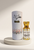 A bottle of Attar Shammim perfume next to its white cylindrical packaging box, displayed on a round white pedestal against a warm beige background.