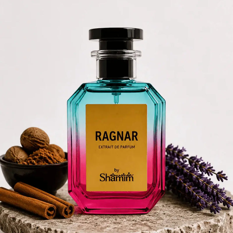 A faceted glass perfume bottle with a black cap, featuring a yellow label that reads 'RAGNAR EXTRAIT DE PARFUM by Shamim'. The bottle has a vibrant blue-to-pink gradient.