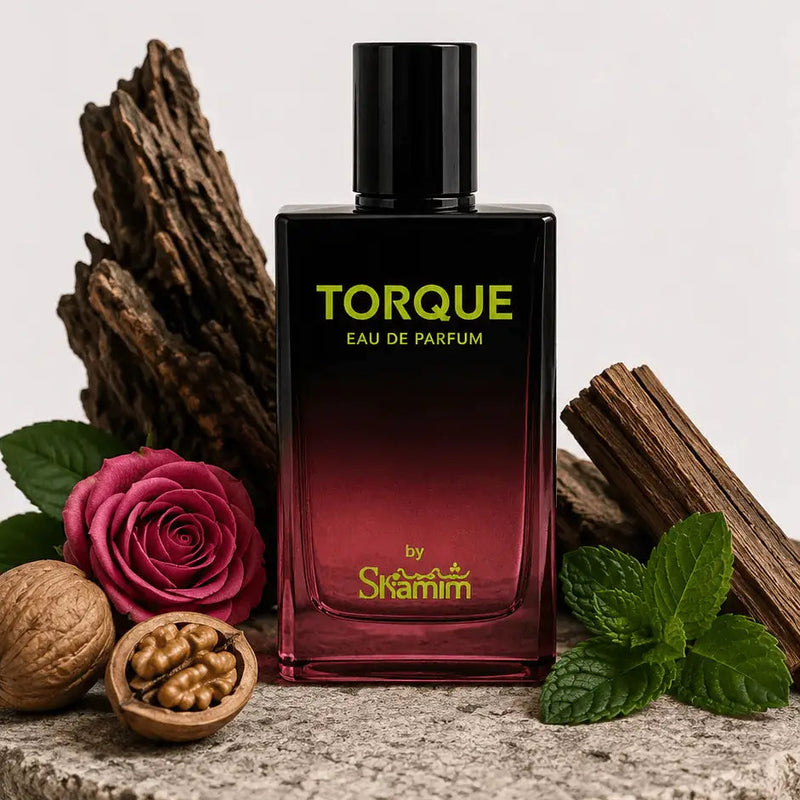 A bottle of Torque Eau de Parfum by Skaramell, featuring a black-to-deep-red gradient glass bottle with gold lettering, styled on a stone plate with a rose, walnuts, cinnamon, and mint leaves against a light gray background.