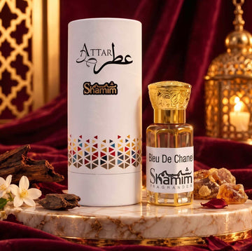 Bleu De Chanel by Chanel fragrance oil in a clear amber bottle with an ornate gold cap and white label beside a white patterned tube